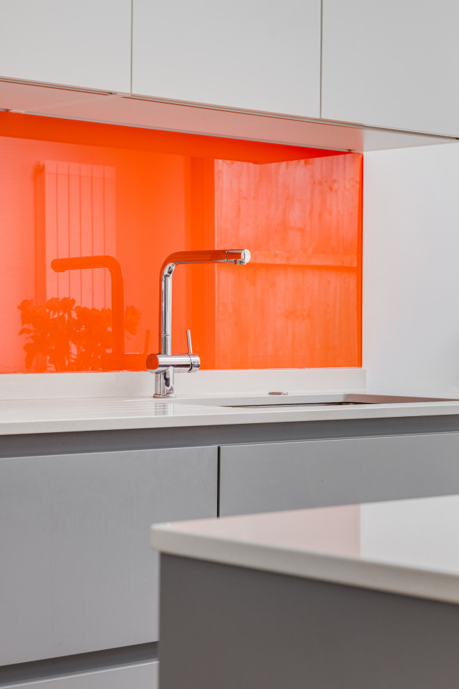 Design ideas for a large contemporary eat-in kitchen in London with a drop-in sink, grey cabinets, quartzite benchtops, orange splashback, glass sheet splashback, coloured appliances, light hardwood floors, brown floor, white benchtop and vaulted.