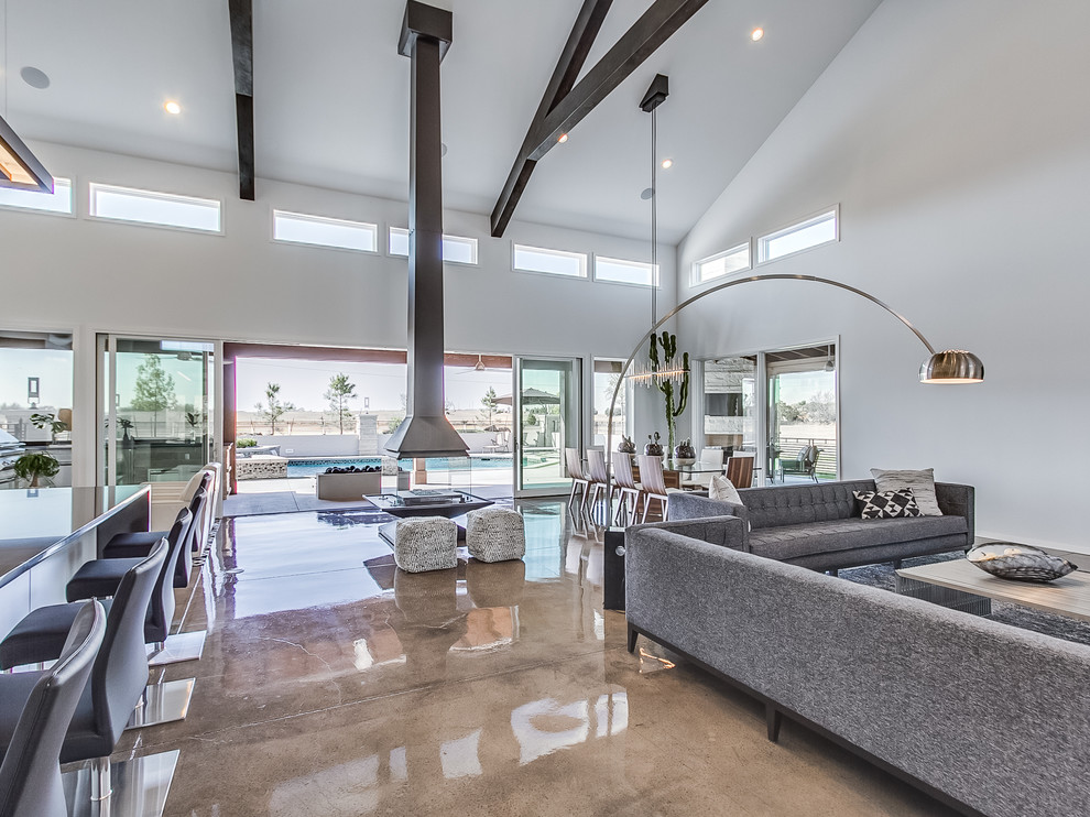 This is an example of an expansive contemporary open concept living room in Oklahoma City with grey walls, concrete floors, a hanging fireplace and a wall-mounted tv.