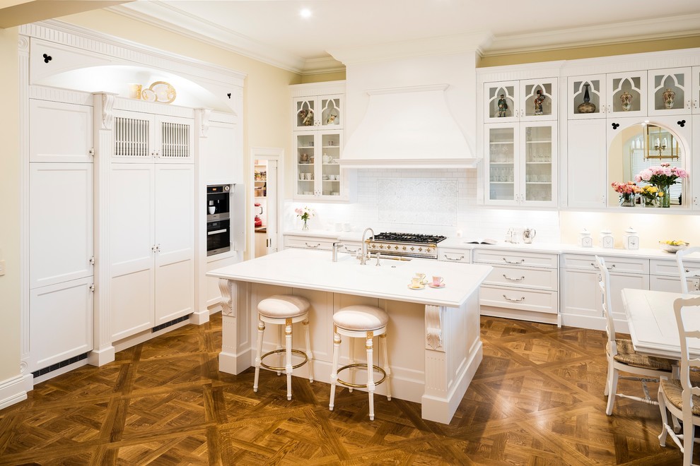 Inspiration for a large country galley eat-in kitchen in Melbourne with a farmhouse sink, shaker cabinets, white cabinets, marble benchtops, white splashback, ceramic splashback, stainless steel appliances, medium hardwood floors, with island, beige floor and white benchtop.