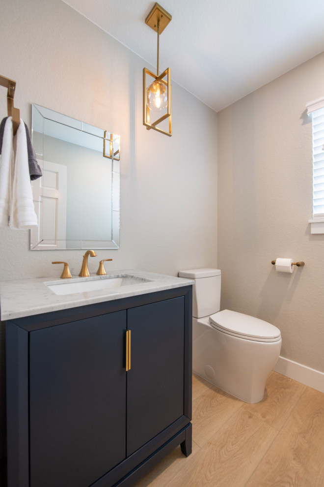 Photo of a small modern cloakroom in Other with flat-panel cabinets, blue cabinets, a one-piece toilet, grey walls, light hardwood flooring, a built-in sink, marble worktops, multi-coloured worktops and a freestanding vanity unit.