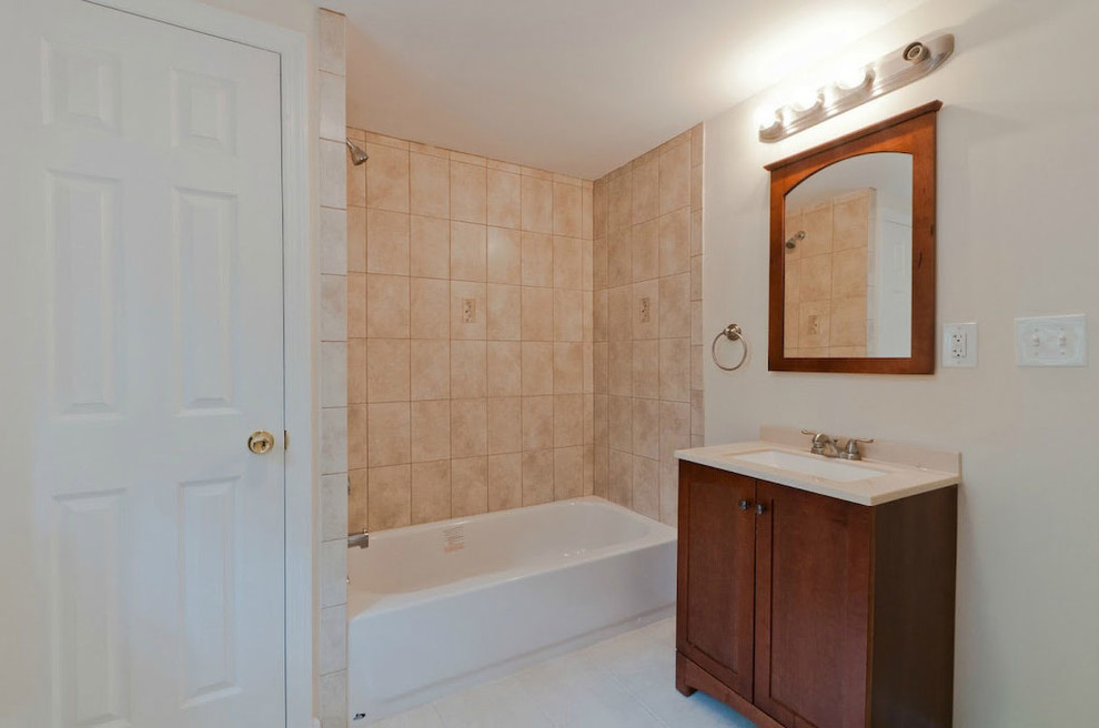 Design ideas for a large traditional master bathroom in New York with shaker cabinets, dark wood cabinets, an alcove tub, a shower/bathtub combo, beige tile, ceramic tile, beige walls, ceramic floors, an undermount sink, limestone benchtops, beige floor and beige benchtops.