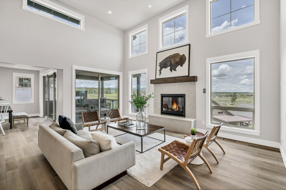 Photo of a large modern open concept living room in Portland with grey walls, medium hardwood floors, a standard fireplace, a stone fireplace surround and vaulted.