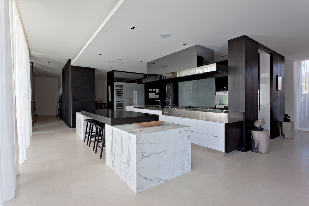 Contemporary open plan kitchen in Perth with flat-panel cabinets, white cabinets, marble benchtops, glass sheet splashback, stainless steel appliances and multiple islands.