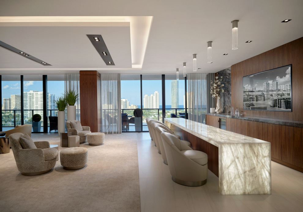 This is an example of a large contemporary seated home bar in Miami with onyx benchtops, porcelain floors and beige benchtop.