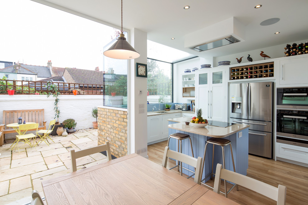 Small contemporary eat-in kitchen in London with blue splashback, stainless steel appliances and with island.