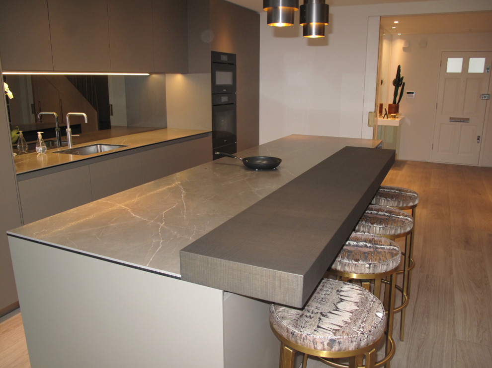 This is an example of a large modern galley open plan kitchen in London with an integrated sink, recessed-panel cabinets, grey cabinets, tile benchtops, grey splashback, glass tile splashback, coloured appliances, porcelain floors, with island, brown floor, green benchtop and coffered.