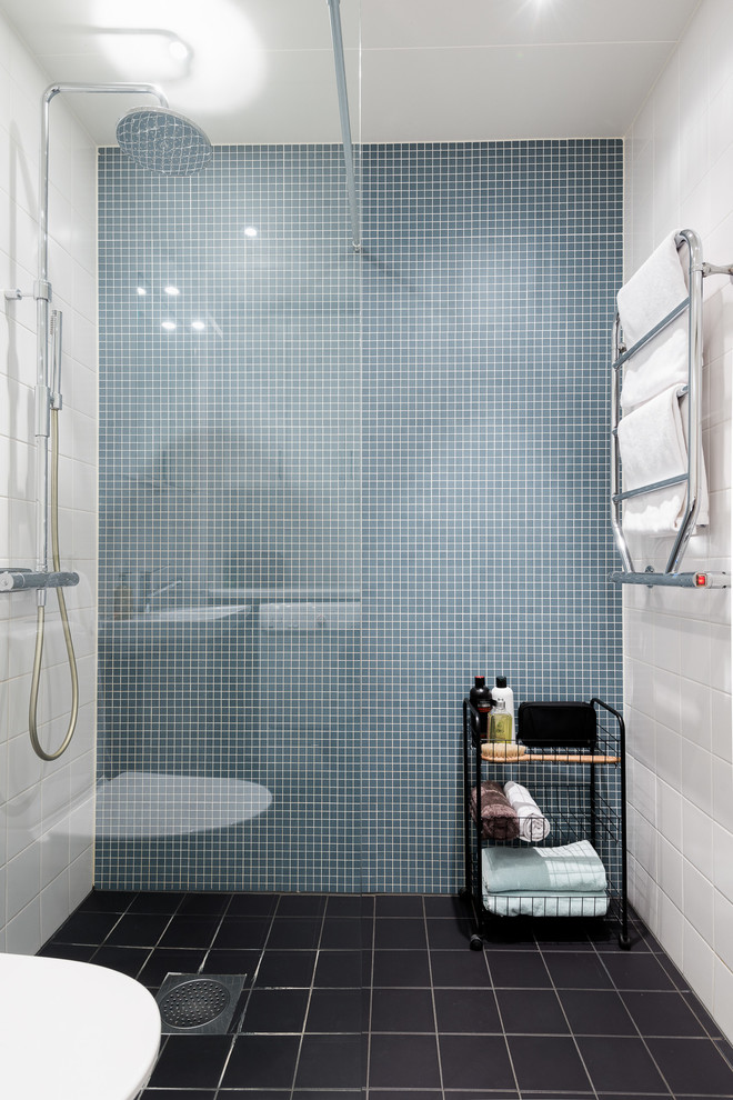This is an example of a small scandinavian 3/4 bathroom in Gothenburg with an open shower, blue tile, mosaic tile, white walls, ceramic floors and black floor.