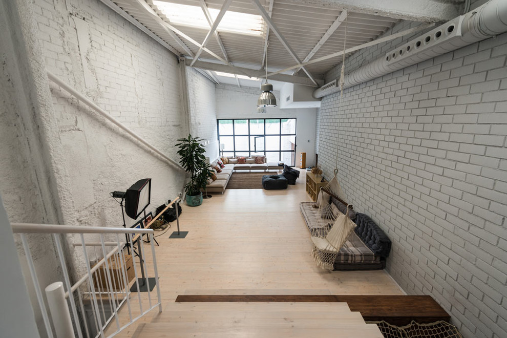 Diseño de sala de estar tipo loft urbana grande sin chimenea con paredes grises, suelo de madera clara, televisor independiente y suelo beige