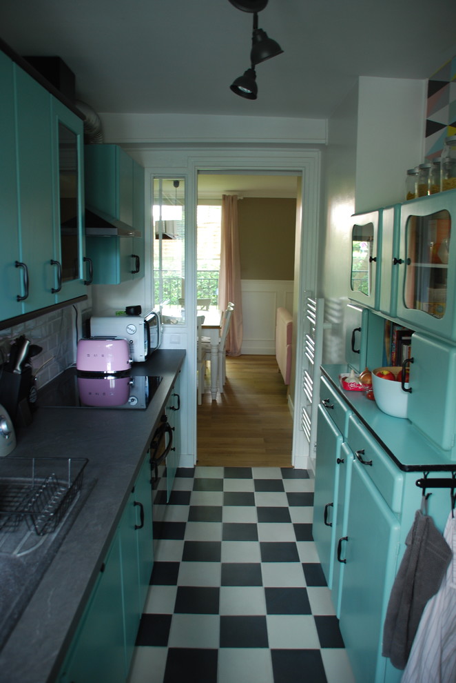 Design ideas for a small midcentury galley separate kitchen in Paris with a double-bowl sink, raised-panel cabinets, green cabinets, laminate benchtops, white splashback, subway tile splashback, black appliances and ceramic floors.