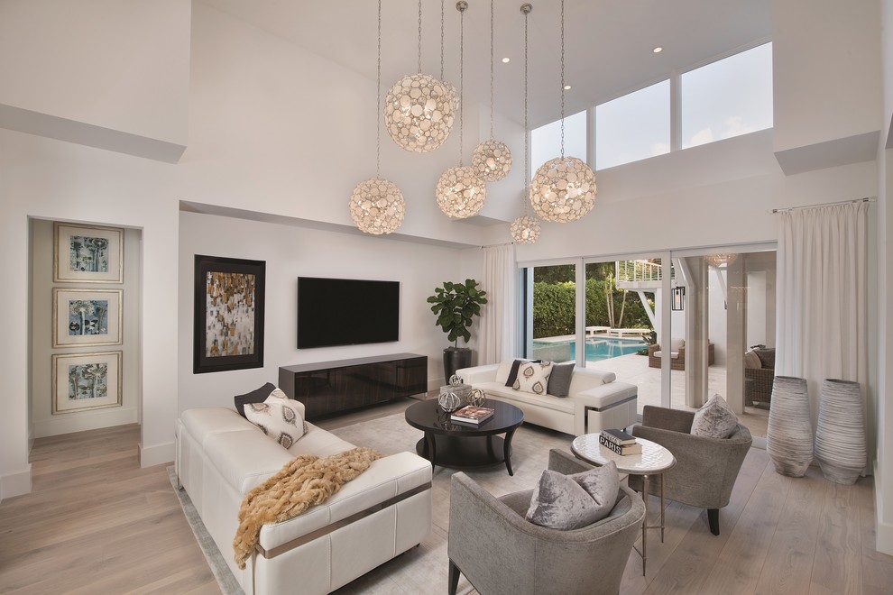 Inspiration for a contemporary family room in Miami with white walls, light hardwood floors and a wall-mounted tv.