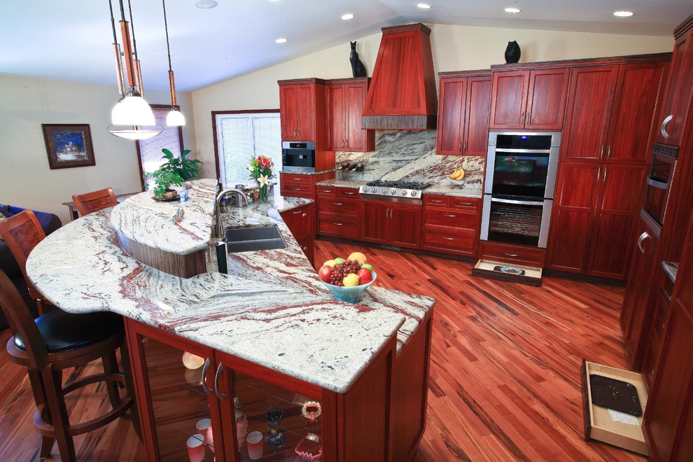 Inspiration for a mid-sized transitional l-shaped medium tone wood floor and brown floor kitchen remodel in Seattle with a double-bowl sink, shaker cabinets, dark wood cabinets, granite countertops, gray backsplash, stone slab backsplash, stainless steel appliances and an island