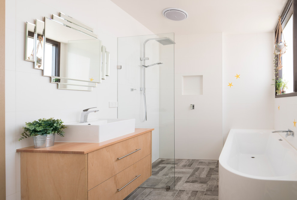 This is an example of a small contemporary master wet room bathroom in Melbourne with flat-panel cabinets, light wood cabinets, white tile, ceramic tile, white walls, ceramic floors, a vessel sink, wood benchtops, grey floor, an open shower, a corner tub and beige benchtops.