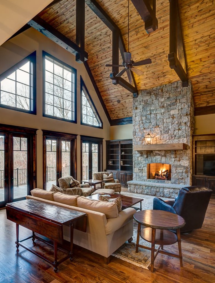 This is an example of a large arts and crafts formal open concept living room in Atlanta with beige walls, dark hardwood floors, a standard fireplace, a stone fireplace surround and a built-in media wall.