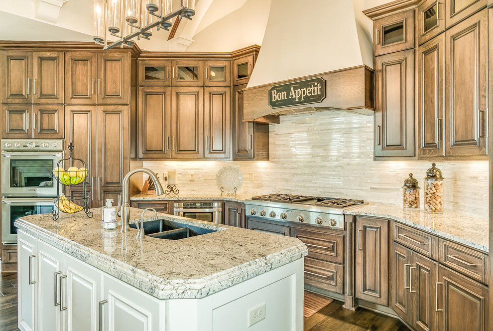 Design ideas for a large transitional u-shaped open plan kitchen in Wichita with a double-bowl sink, beaded inset cabinets, dark wood cabinets, granite benchtops, beige splashback, stainless steel appliances, dark hardwood floors and multiple islands.