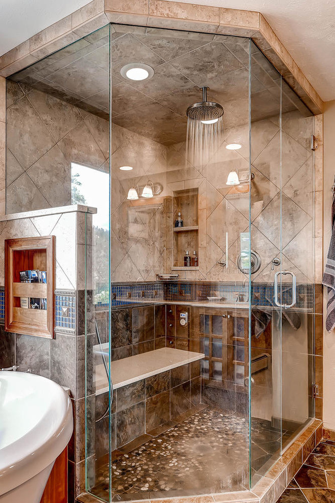 Photo of a large country master bathroom in Denver with flat-panel cabinets, light wood cabinets, a freestanding tub, a double shower, blue tile, mosaic tile, beige walls, concrete floors, an undermount sink and limestone benchtops.