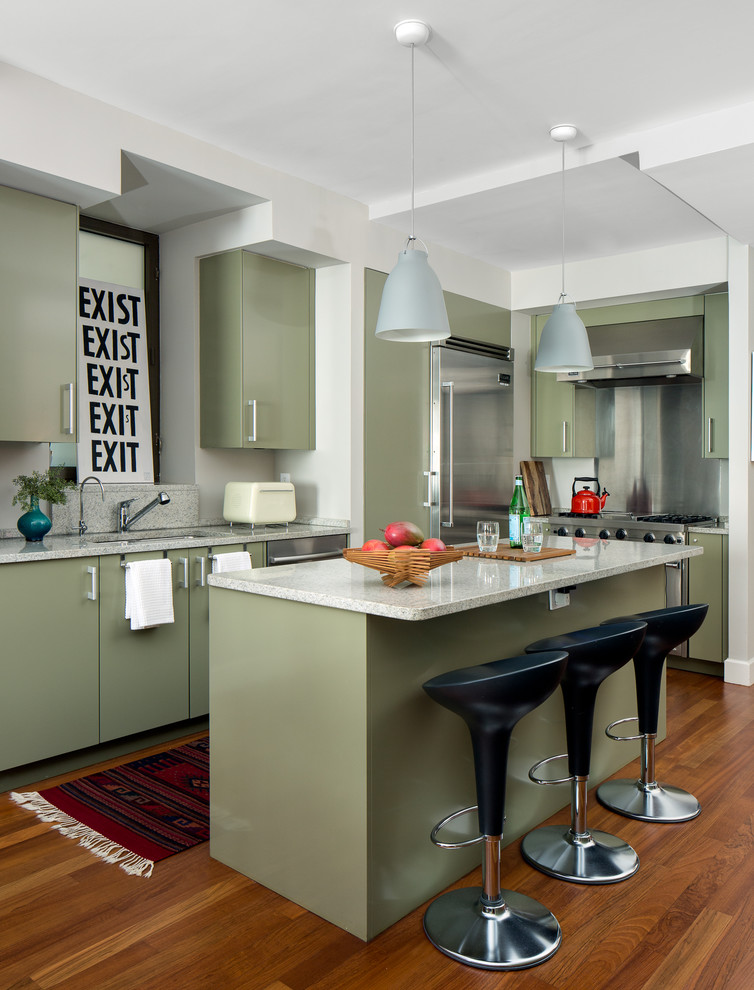 This is an example of a midcentury kitchen in New York with an undermount sink, flat-panel cabinets, green cabinets, metallic splashback, stainless steel appliances, medium hardwood floors and with island.
