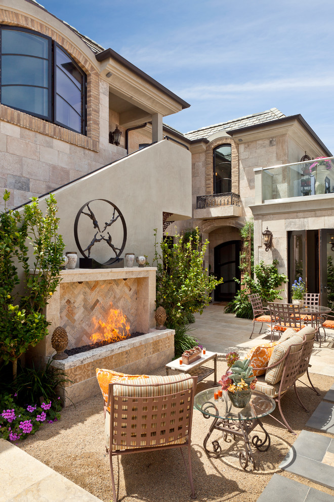 Mediterranean patio in Orange County with a fire feature and no cover.
