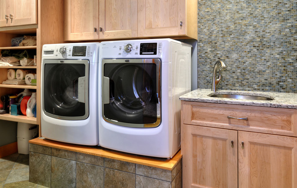 Photo of a mid-sized transitional laundry room in New York with a single-bowl sink, recessed-panel cabinets, light wood cabinets, granite benchtops, ceramic floors, a side-by-side washer and dryer and brown floor.