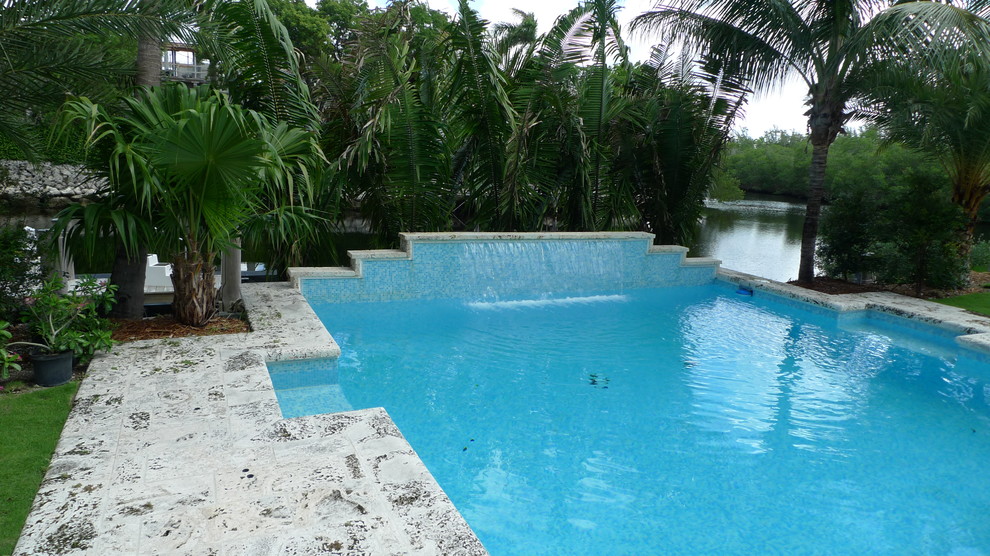 Design ideas for a large asian side yard pool in Miami with natural stone pavers.