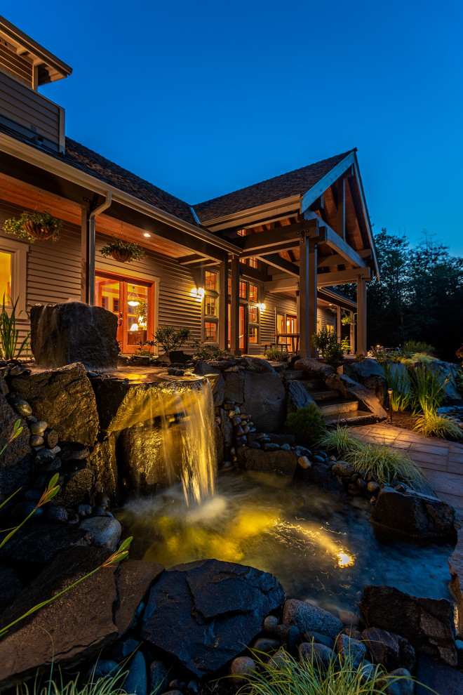 Immagine di un ampio giardino stile americano dietro casa con una cascata e pavimentazioni in pietra naturale
