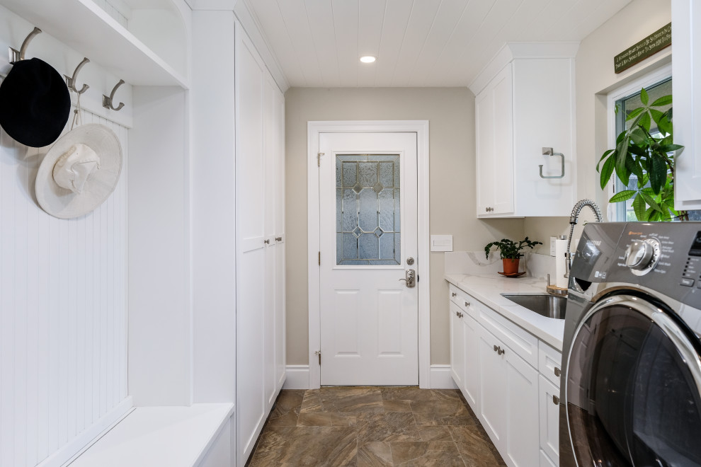 Inspiration for a mid-sized traditional galley dedicated laundry room in Sacramento with an undermount sink, shaker cabinets, white cabinets, quartz benchtops, white splashback, engineered quartz splashback, beige walls, porcelain floors, a side-by-side washer and dryer, brown floor, white benchtop and wood.