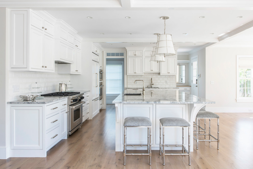 Lower Cliff Rd. - Inspiration for a huge coastal l-shaped eat-in kitchen remodel in Boston with an undermount sink, shaker cabinets, white cabinets, marble countertops, white backsplash, glass tile backsplash, paneled appliances and an island