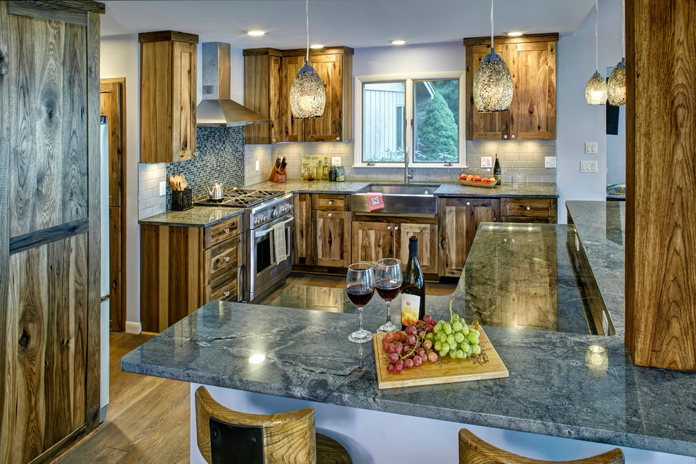 Mid-sized mountain style light wood floor kitchen photo with a farmhouse sink, recessed-panel cabinets, granite countertops, glass tile backsplash, stainless steel appliances and an island