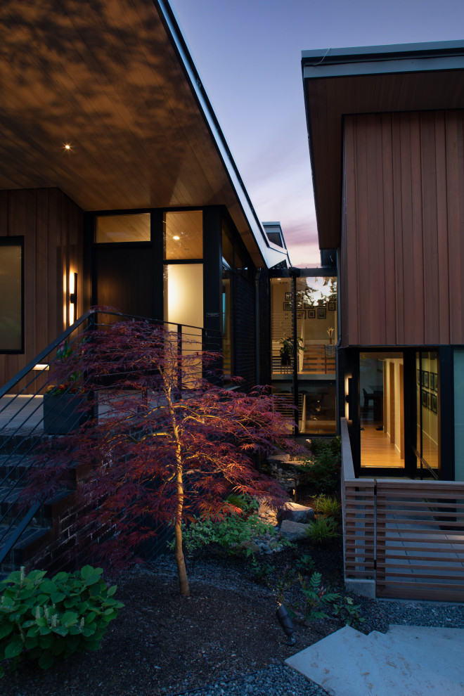 Cette photo montre un grand porche d'entrée de maison avant tendance avec une moustiquaire, une extension de toiture et un garde-corps en bois.