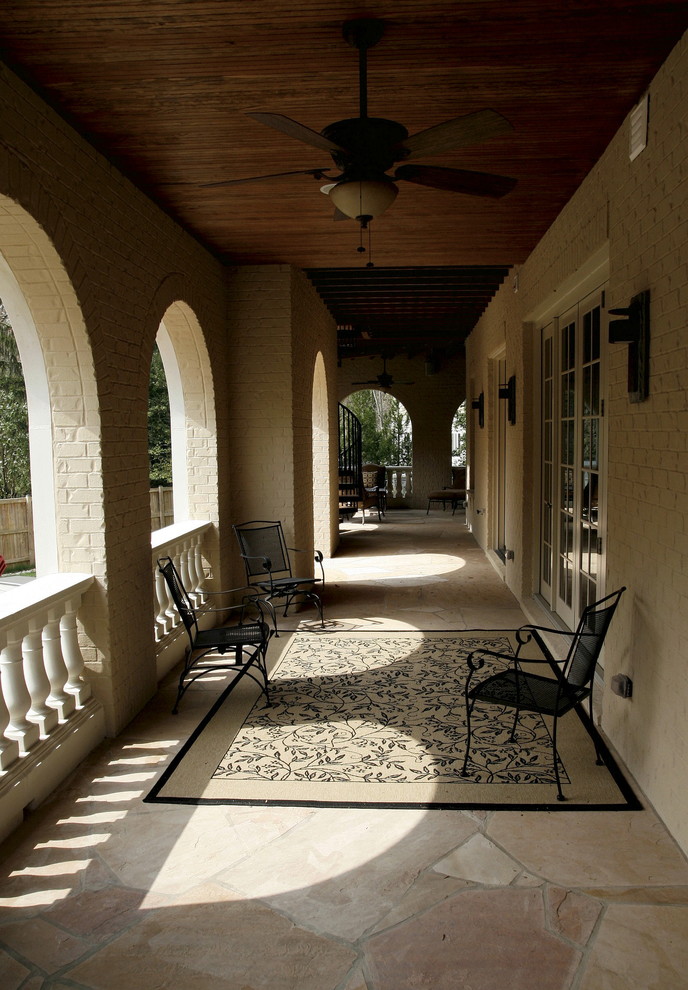 Inspiration for a large mediterranean side yard verandah in Baltimore with natural stone pavers and a roof extension.