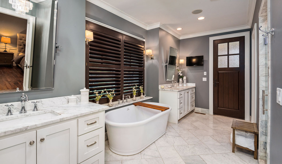 Arts and crafts master bathroom in Kansas City with white cabinets, a freestanding tub, an alcove shower, gray tile, grey walls, an undermount sink, granite benchtops, yellow floor, a hinged shower door and white benchtops.