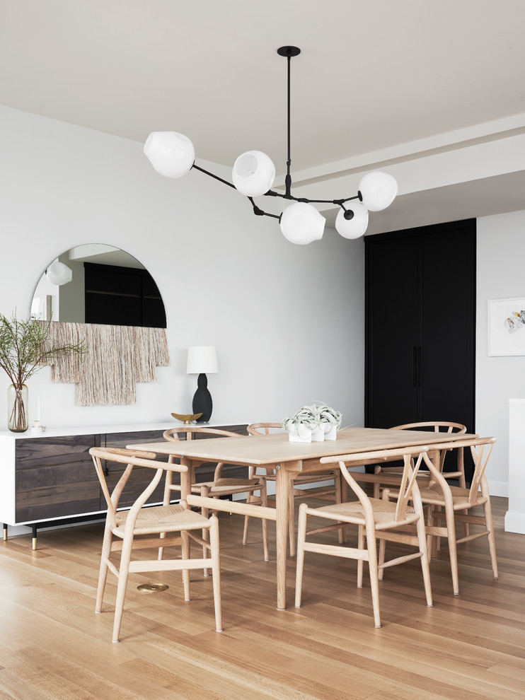 Inspiration for a scandinavian dining room in New York with white walls, light hardwood floors and no fireplace.