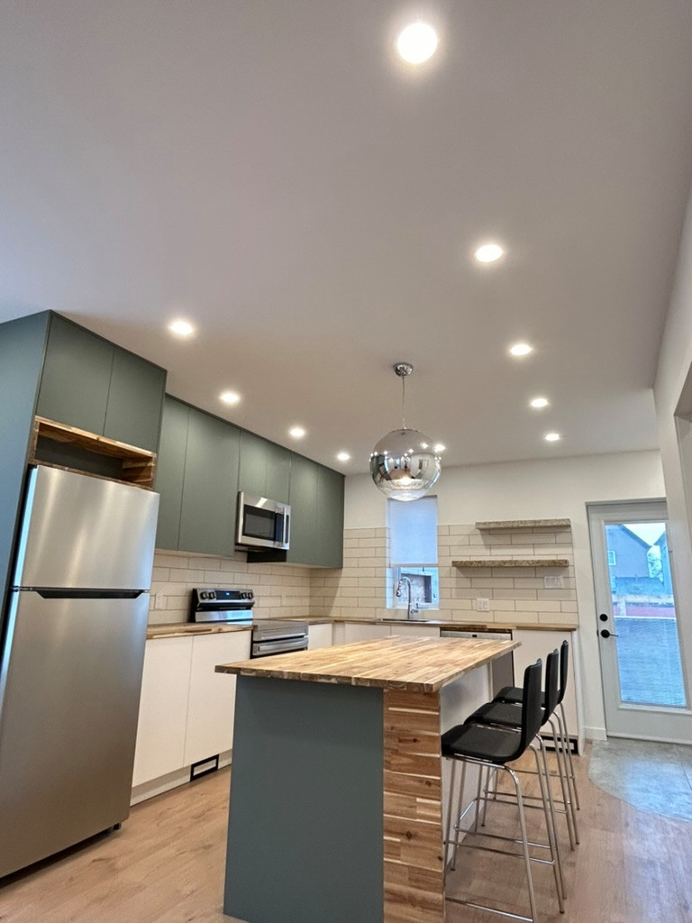 Inspiration for a modern medium tone wood floor eat-in kitchen remodel in Other with a single-bowl sink, flat-panel cabinets, green cabinets, wood countertops, white backsplash, ceramic backsplash, st