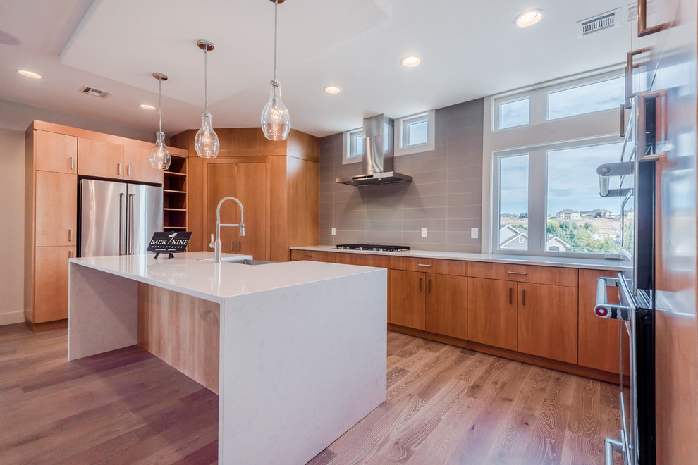 Large transitional u-shaped dark wood floor eat-in kitchen photo with a farmhouse sink, flat-panel cabinets, light wood cabinets, quartz countertops, gray backsplash, subway tile backsplash, stainless steel appliances and an island