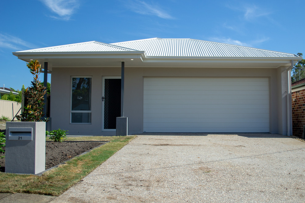 Photo of a small contemporary one-storey brick beige house exterior in Brisbane with a hip roof and a metal roof.