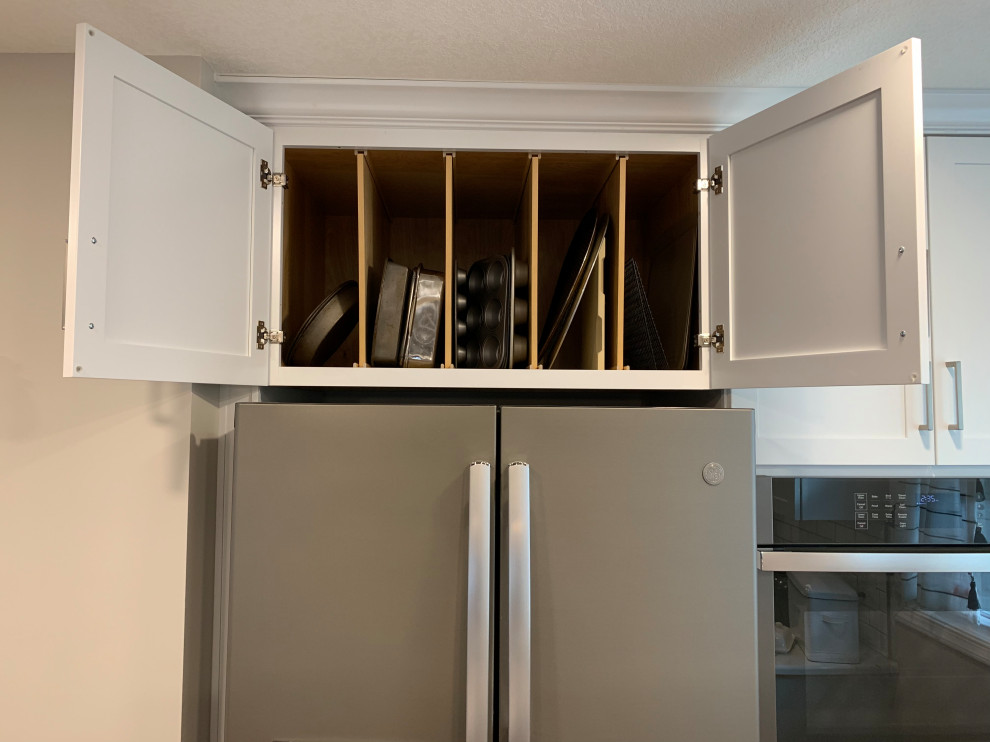 Example of a large transitional u-shaped vinyl floor and brown floor open concept kitchen design with an undermount sink, shaker cabinets, white cabinets, quartz countertops, white backsplash, ceramic backsplash, stainless steel appliances, an island and white countertops