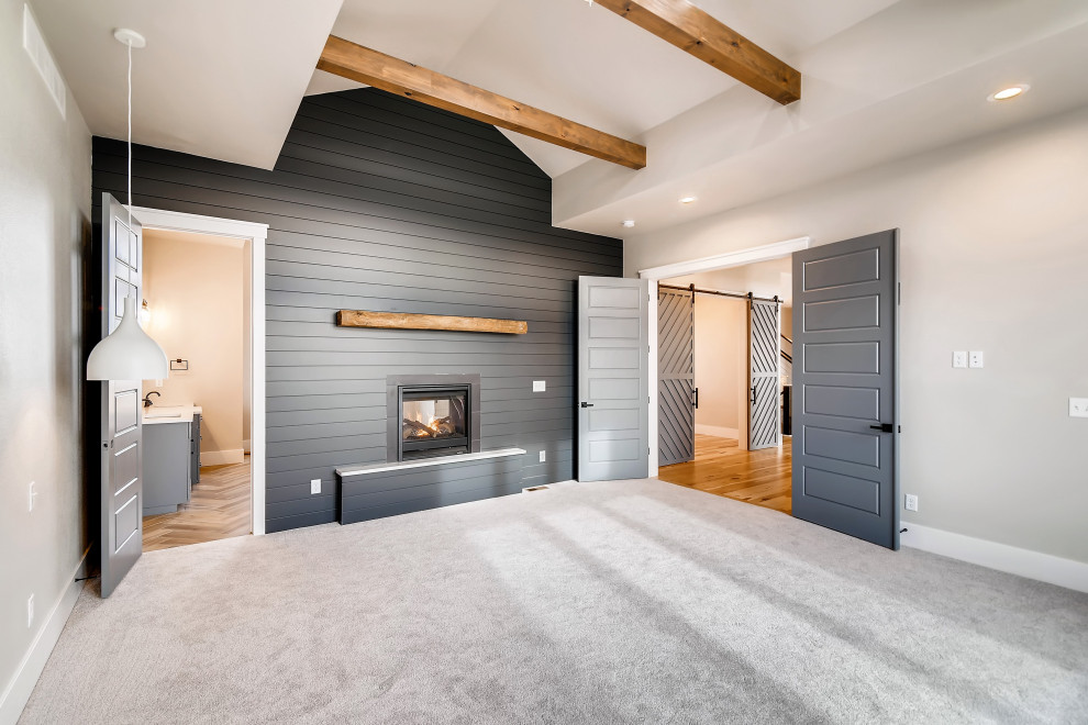 Cette photo montre une grande chambre nature avec un mur gris, une cheminée double-face, un manteau de cheminée en carrelage, un sol gris, poutres apparentes et du lambris de bois.