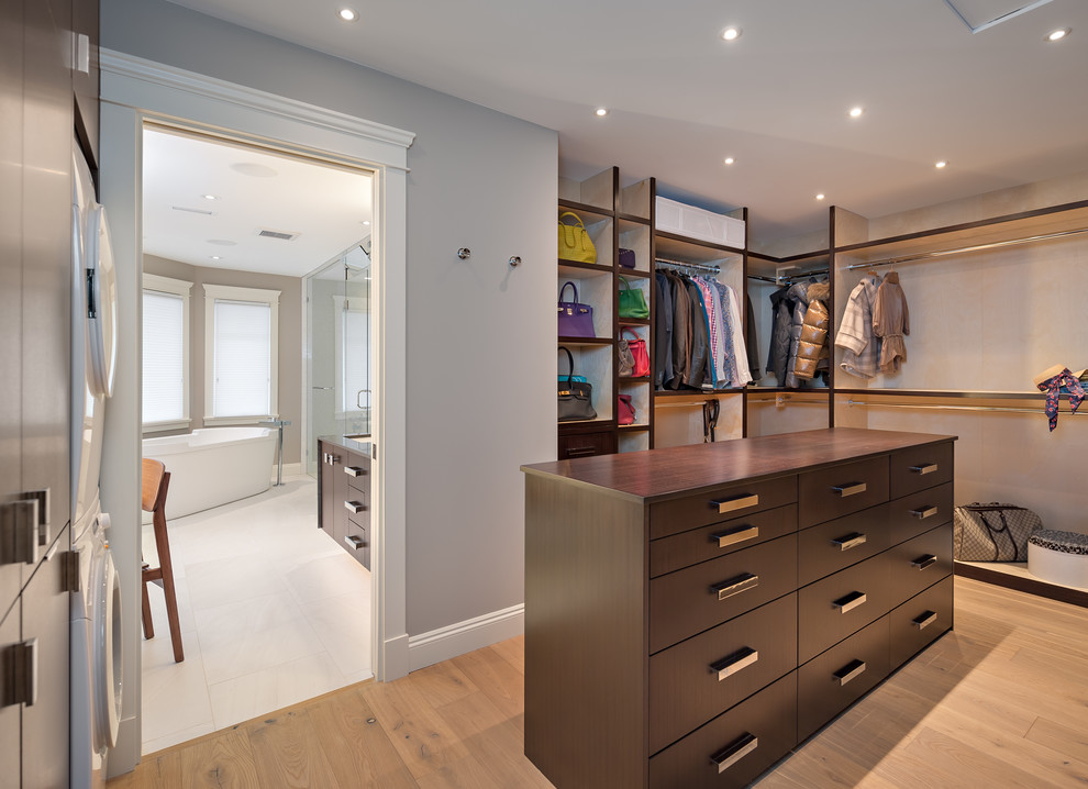 Large transitional gender-neutral medium tone wood floor and beige floor walk-in closet photo in Vancouver with flat-panel cabinets and dark wood cabinets