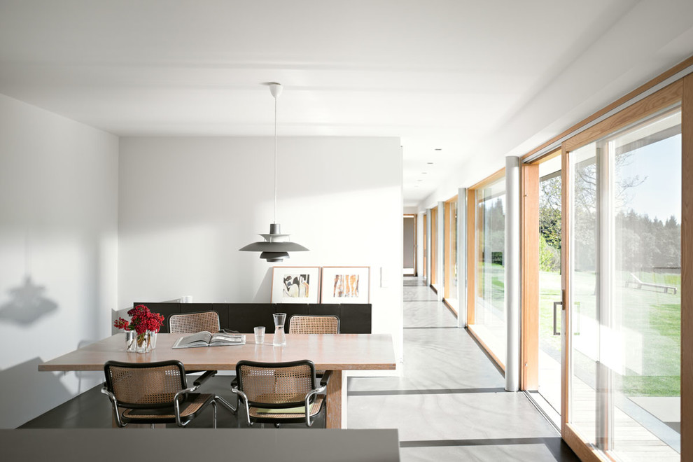 Modernes Esszimmer mit weißer Wandfarbe und Betonboden in Köln