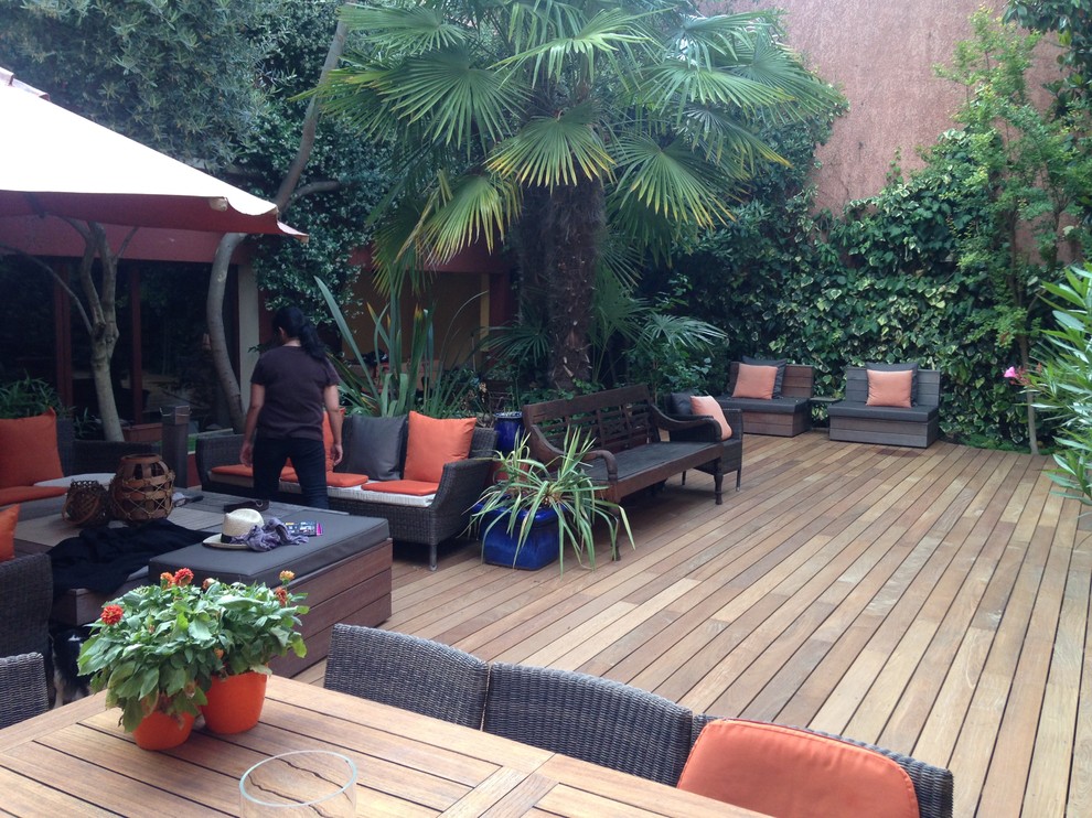 Photo of an expansive tropical backyard deck in Paris with a fire feature and no cover.