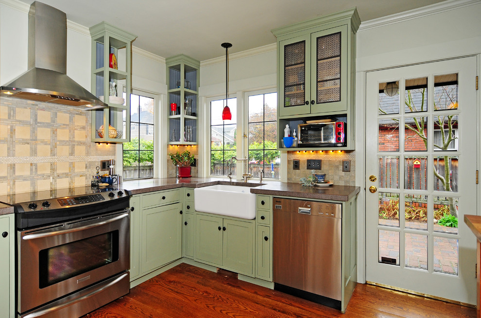 This is an example of a mid-sized transitional u-shaped kitchen pantry in Seattle with a farmhouse sink, shaker cabinets, green cabinets, concrete benchtops, green splashback, stone tile splashback, stainless steel appliances, dark hardwood floors and with island.