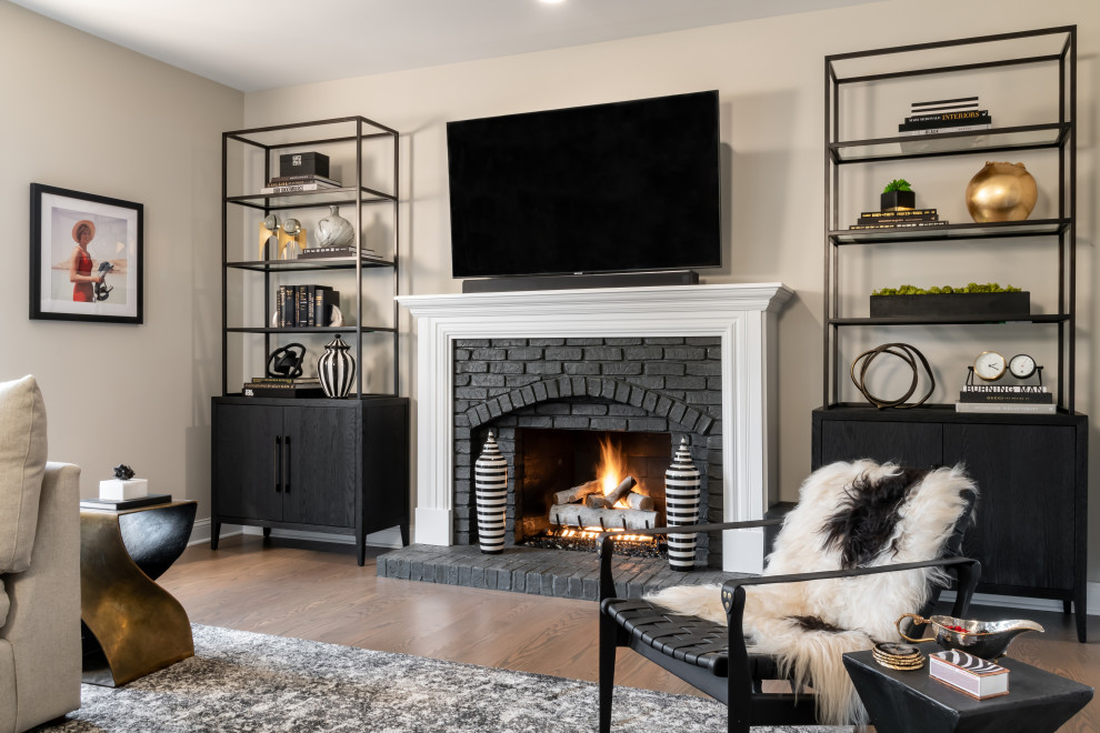 Inspiration for a medium sized classic enclosed games room in St Louis with a home bar, grey walls, medium hardwood flooring, a standard fireplace, a brick fireplace surround, a wall mounted tv and brown floors.