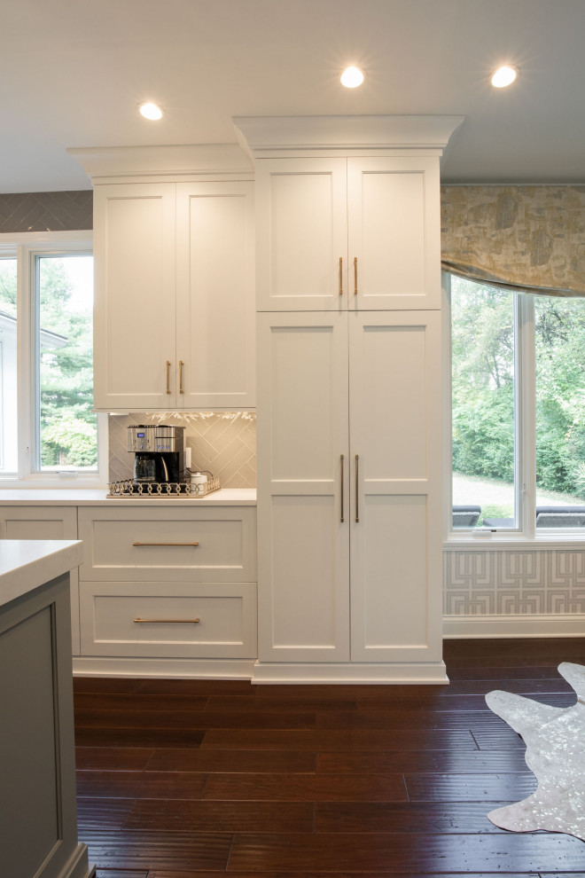 Photo of a large transitional u-shaped eat-in kitchen in Indianapolis with an undermount sink, recessed-panel cabinets, white cabinets, quartz benchtops, white splashback, ceramic splashback, stainless steel appliances, dark hardwood floors, with island, brown floor and white benchtop.