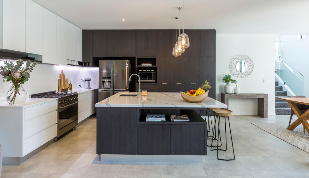Design ideas for a contemporary l-shaped eat-in kitchen in Gold Coast - Tweed with an undermount sink, flat-panel cabinets, black cabinets, white splashback, stainless steel appliances, with island, grey floor and white benchtop.