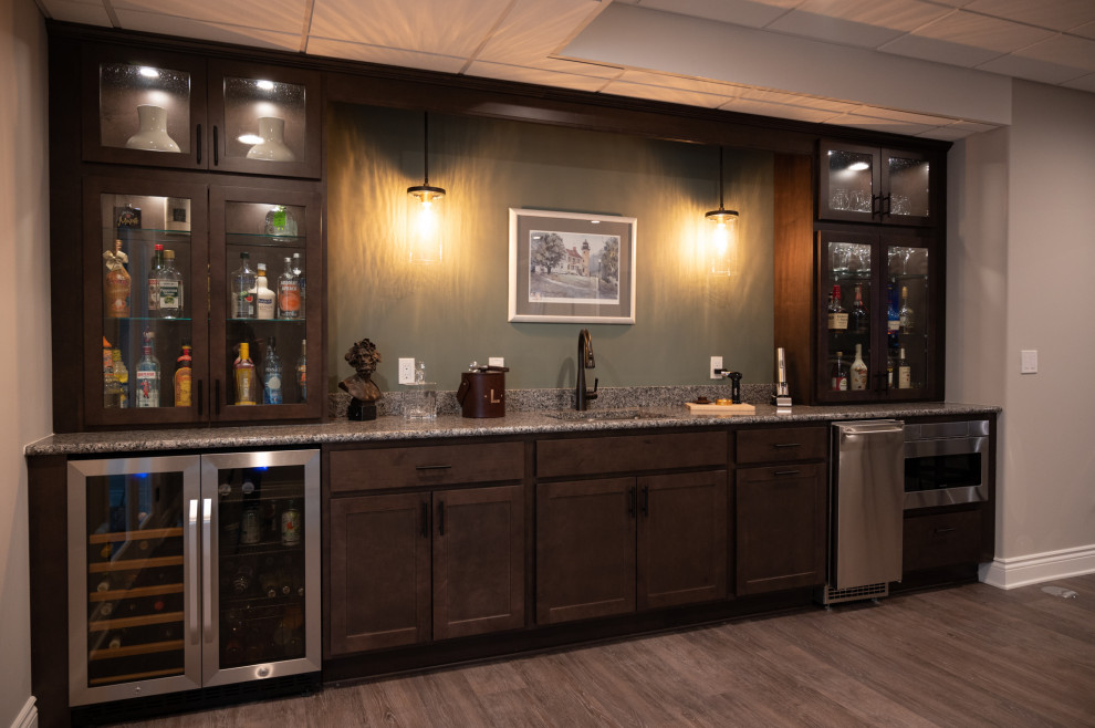 Design ideas for a small modern single-wall wet bar in Detroit with an undermount sink, glass-front cabinets, brown cabinets, wood benchtops, multi-coloured splashback, granite splashback, vinyl floors, multi-coloured floor and brown benchtop.