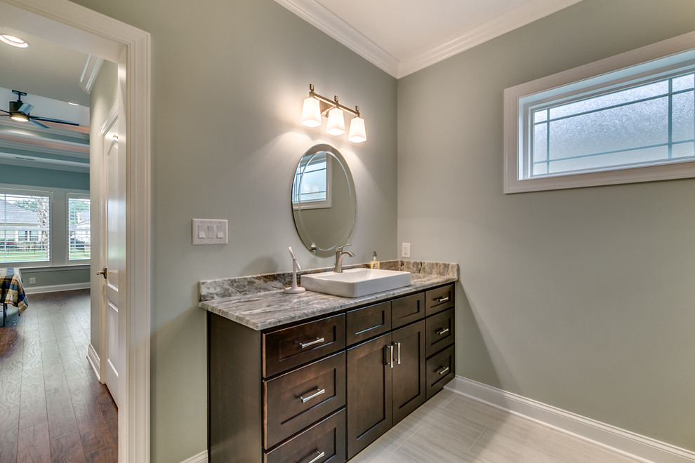 Inspiration for a mid-sized transitional 3/4 porcelain tile and beige floor bathroom remodel with shaker cabinets, dark wood cabinets, gray walls, a vessel sink, granite countertops and gray countertops