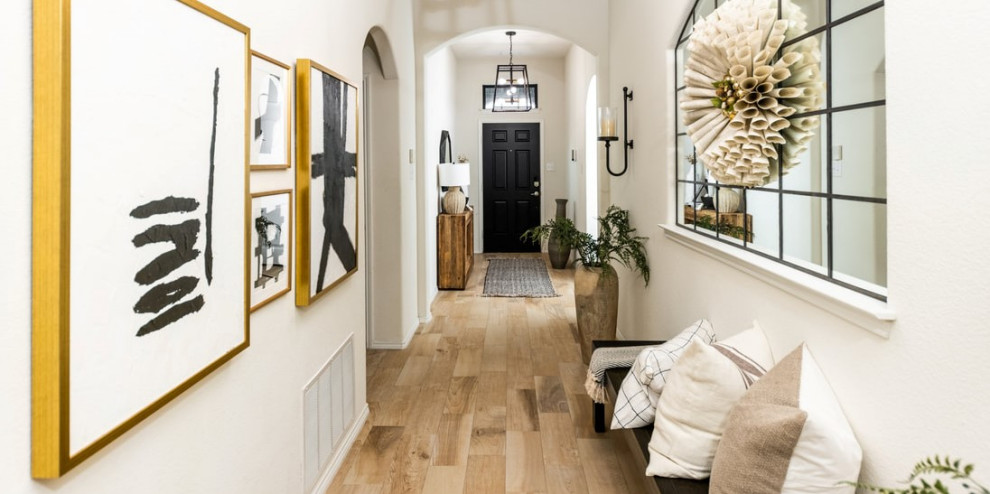 This is an example of a large farmhouse foyer in Dallas with white walls, travertine flooring, a single front door, a black front door and beige floors.