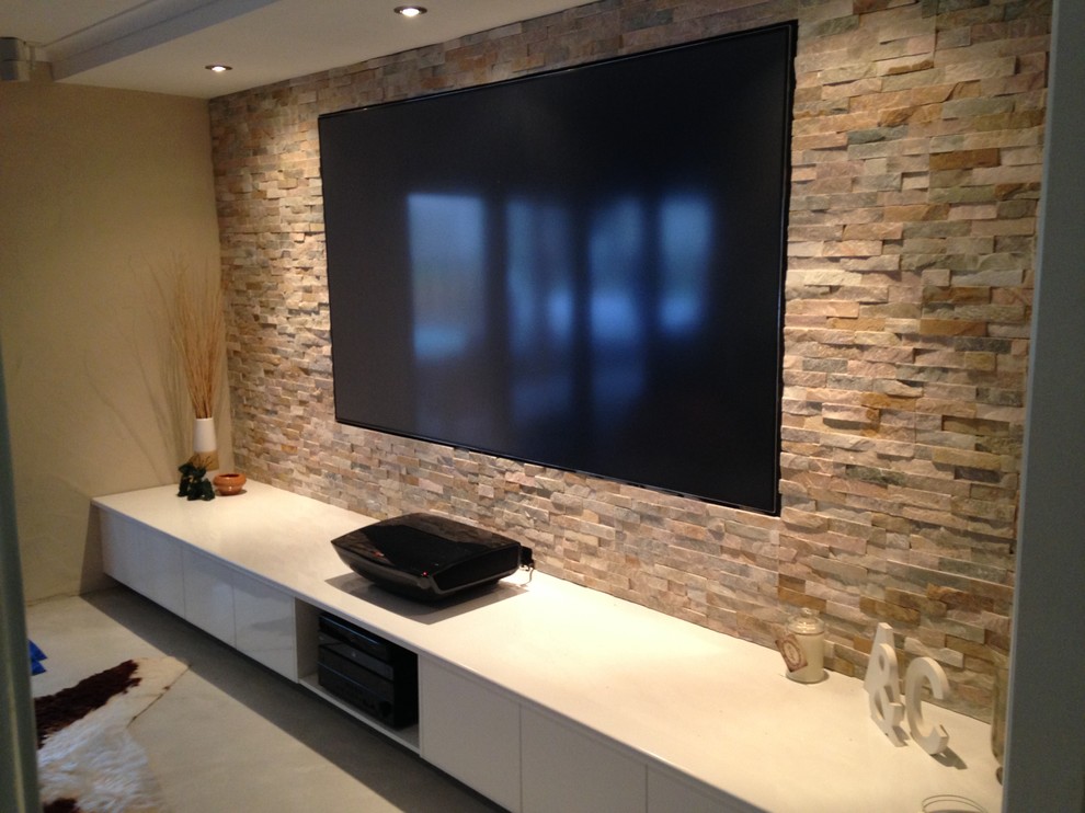 Large modern open concept home theatre in Sunshine Coast with multi-coloured walls, concrete floors and a built-in media wall.