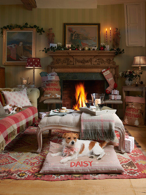Holiday Decor Ideas for Dog Lovers - English christmas scene.  Living room decorated in rosy plaids with firs place and socking.  Dog in foreground lying on pillow type pink dog bed. 