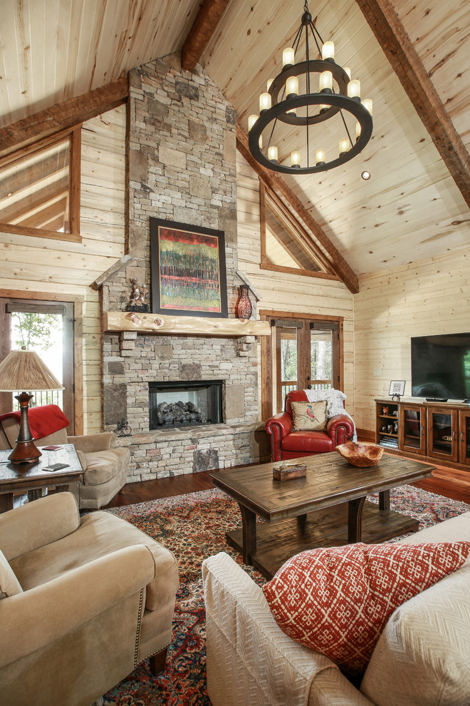Example of a mountain style living room design in New Orleans with beige walls, a standard fireplace, a stone fireplace and a tv stand
