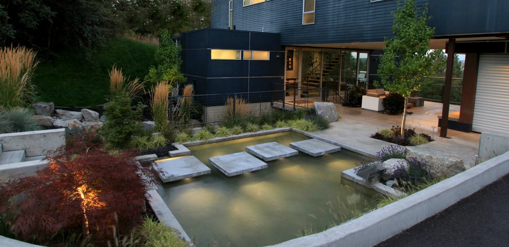 This is an example of a large modern backyard full sun driveway in Seattle with with pond and concrete pavers.